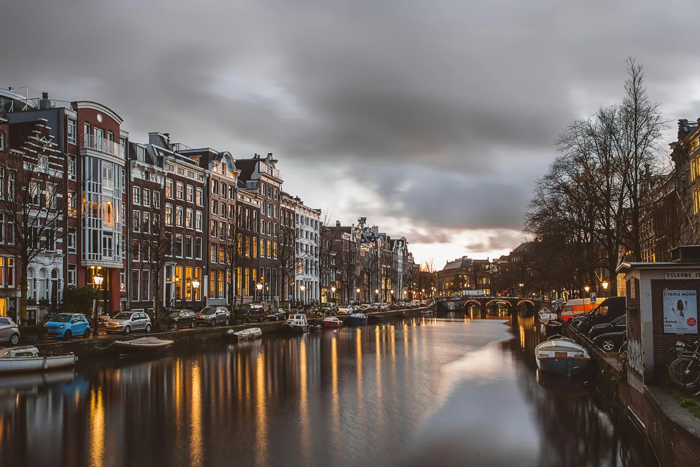 Canal houses and moored boats along an Amsterdam canal at dusk